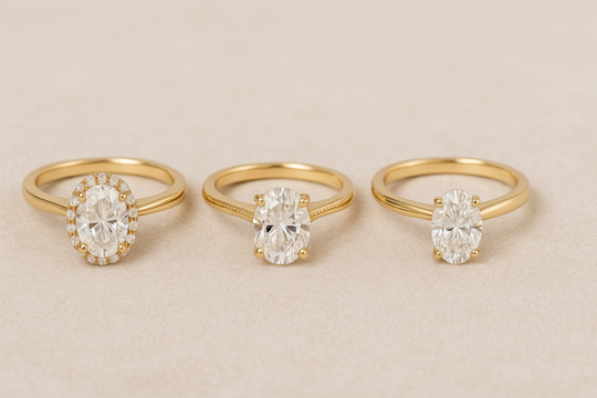 Three oval moissanite engagement rings side by side: halo, hidden halo, and solitaire, all in 14k gold, on soft neutral background